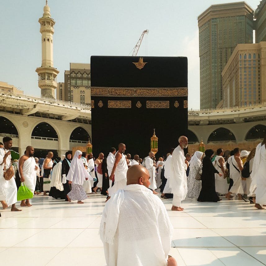 Man Kneeling and Pilgrims Walking at Great Mosque in Mecca